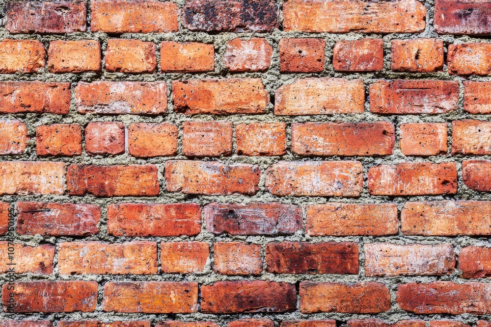 Fototapeta premium A textured wall made of red bricks with mortar in between.