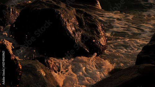 Sea waves hitting the rocky coast at sunset