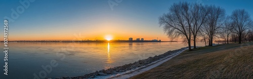 A breathtaking sunrise panorama over the water reflecting hues of orange and blue near the shoreline