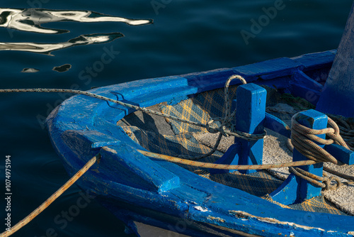 Old wooden fishing boat moored in the marina. Mooring rope between the boat and the port. Cute little fishing boat. photo