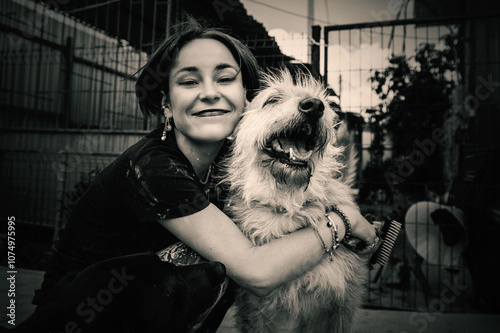 Dog at the shelter. Lonely dogs in cage with cheerful woman volunteer. photo