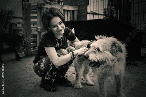 Dog at the shelter. Lonely dogs in cage with cheerful woman volunteer. photo