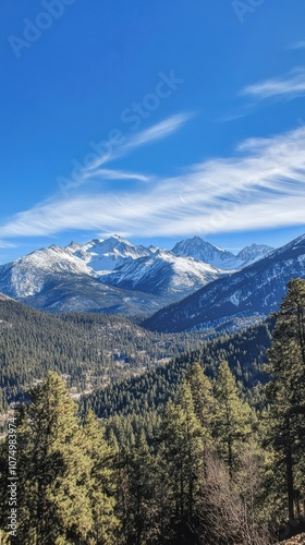 Majestic snow-capped mountains rise under a clear blue sky, surrounded by lush green forests and distant peaks at sunrise