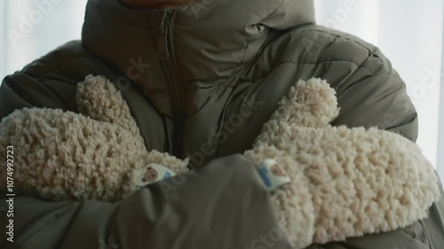 A man in a winter jacket and warm gloves is freezing from the cold.
A man in a very cold winter.
It's frosty outside and a man is trying to warm up.
A man in winter gloves.
Fluffy gloves on hands