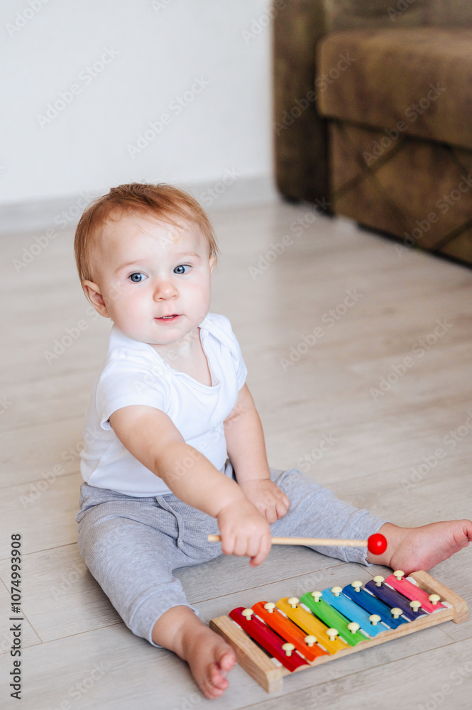 little girl in white bodysuit sitting on floor and playing with colorful toy little girl in white bodysuit sitting on floor and playing with colorful toy