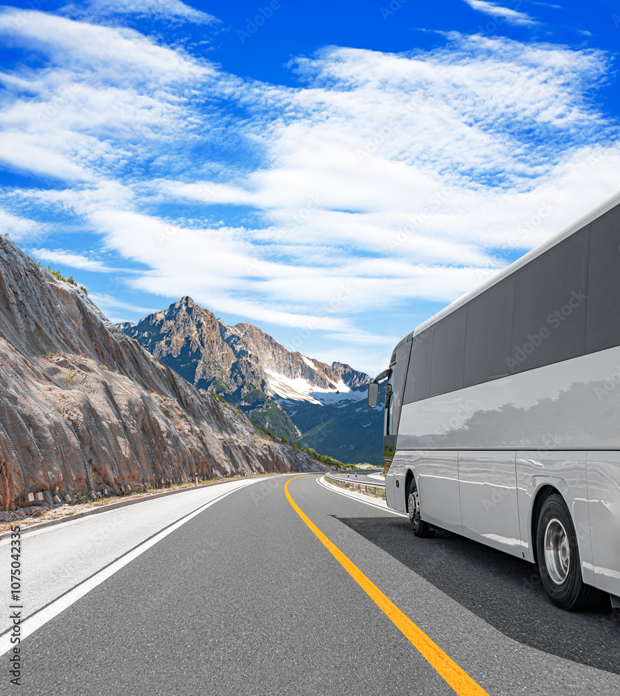 A white tourist bus travels along a picturesque mountain road.