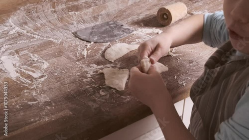 Little 5-year-old girl kneads dough in kitchen, mastering cooking skills, flour on countertop, joyful childhood, family teamwork and teaching children responsibility from young age