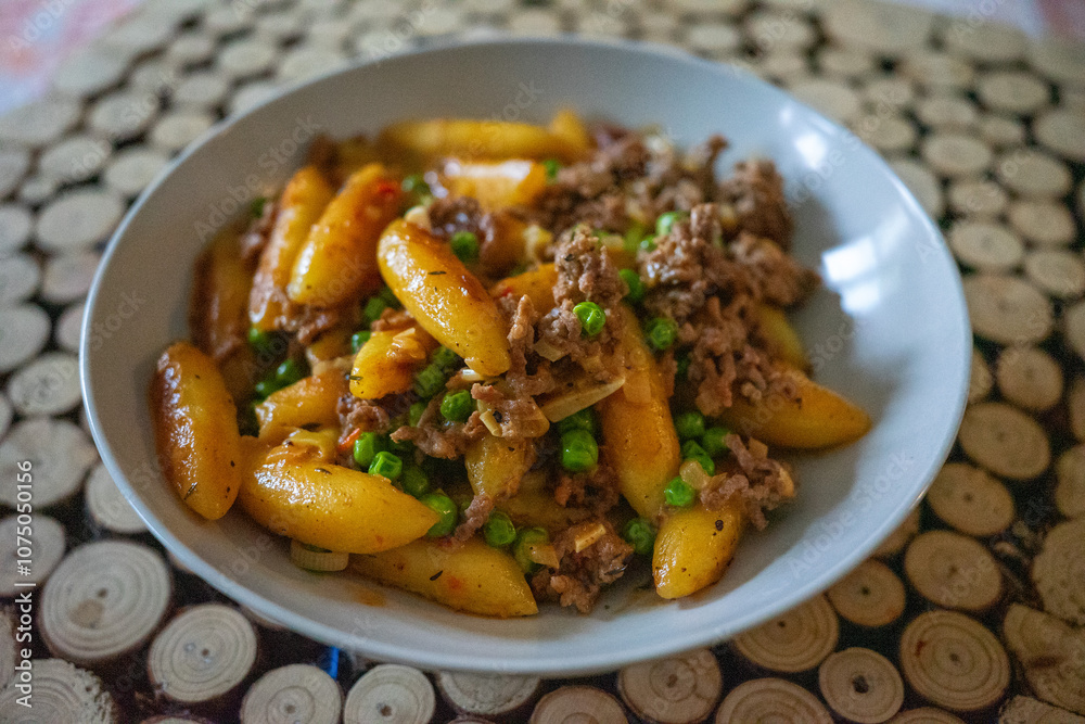 Plate of gnocchi with minced meat and green peas served on a patterned placemat. Plate of gnocchi with minced meat and green peas served on a patterned placemat.