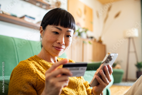 Woman making online payment with credit card and smartphone at home photo