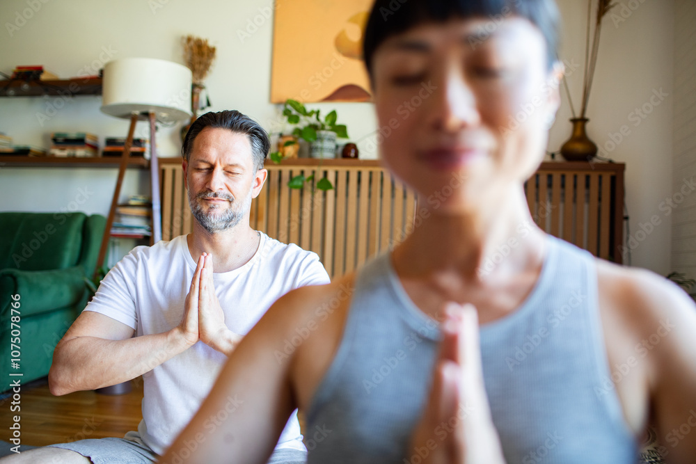 Fototapeta premium Couple doing yoga together at living room floor