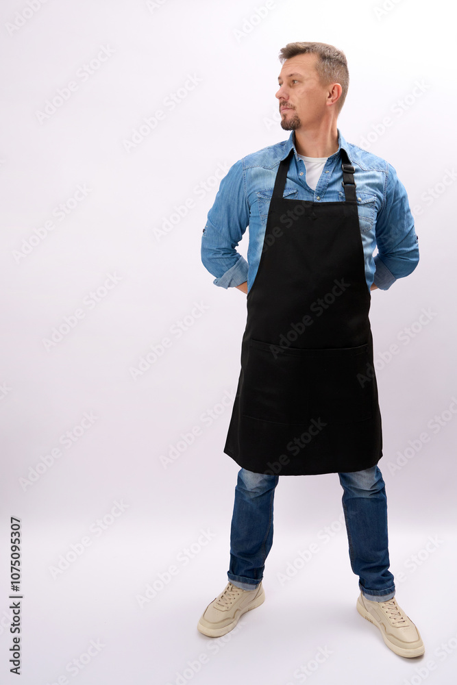 Full body portrait of handsome man in black apron standing with his hands behind his back, white background with copy space, vertical Full body portrait of handsome man in black apron standing with his hands behind his back, white background with copy space, vertical