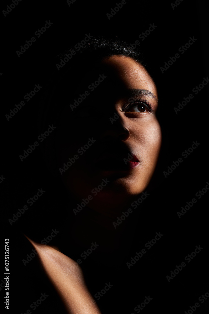 A young African American woman with striking red lips in a dimly lit studio. A young African American woman with striking red lips in a dimly lit studio.