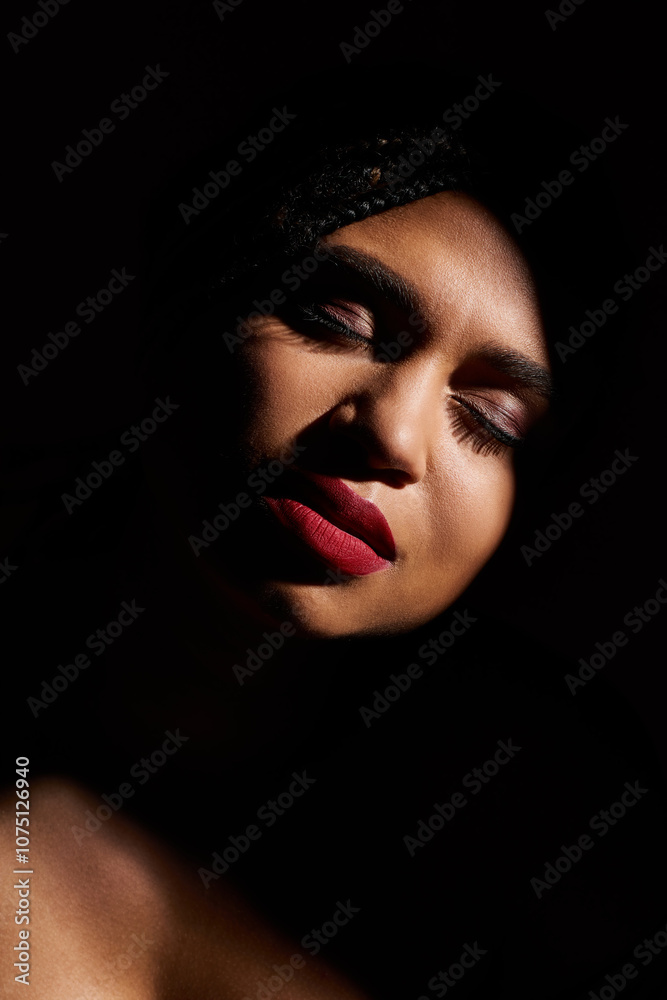 A stylish African American woman with bold red lips against a dark backdrop. A stylish African American woman with bold red lips against a dark backdrop.