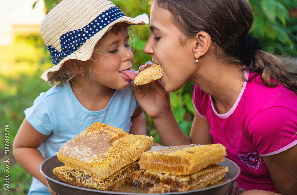 A child eats honey from a comb. Selective focus. A child eats honey from a comb. Selective focus.