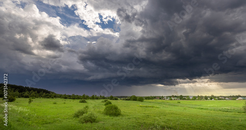 A field of grass is covered in dark clouds, and the sky is overcast