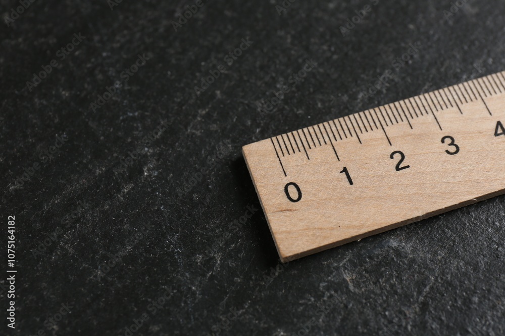 One wooden ruler on black table, closeup. Space for text One wooden ruler on black table, closeup. Space for text