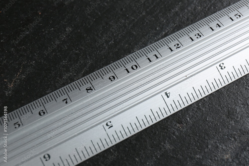 One metal ruler on black table, above view One metal ruler on black table, above view