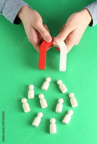 Man with magnet attracting game pieces at green table, above view