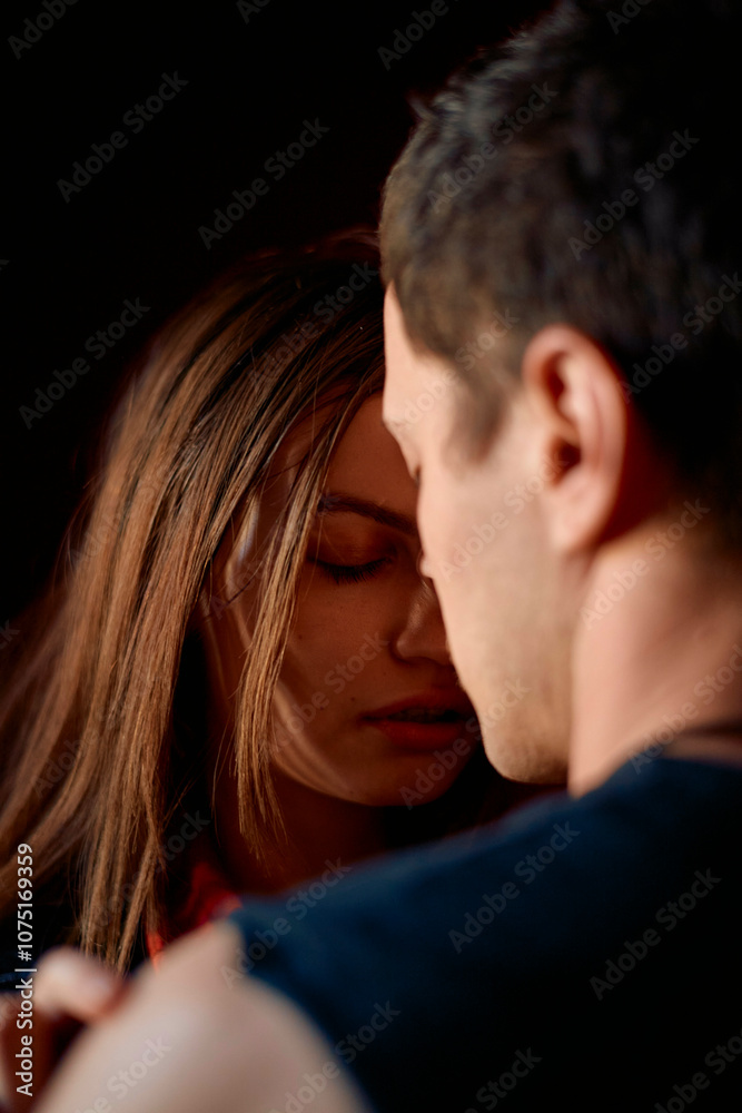 An intimate moment between a young woman and a man as she closes her eyes and leans her forehead against his, bathed in soft light. An intimate moment between a young woman and a man as she closes her eyes and leans her forehead against his, bathed in soft light.