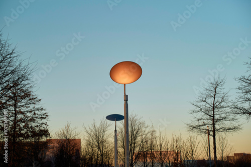 Street lamp glowing against the twilight sky amidst bare trees, Berlin, Germany photo