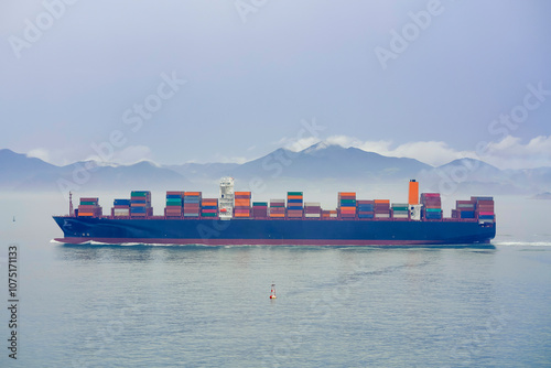 Cargo ship sailing on a foggy ocean with a tranquil mountain backdrop, Busan, Korea