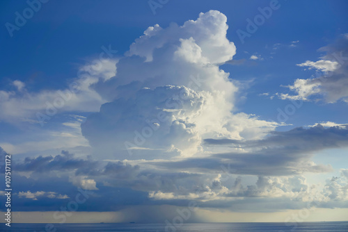 Majestic cumulus cloud towering over a serene sea under a blue sky with soft light piercing through, South China Sea