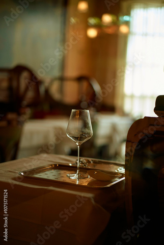 A wine glass casts a soft reflection on an elegant dining table set in a restaurant with a blurred background. photo