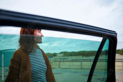 Wallpaper Mural Side view of a smiling woman in a striped shirt seen through a car window with a clear sky in the background. Torontodigital.ca