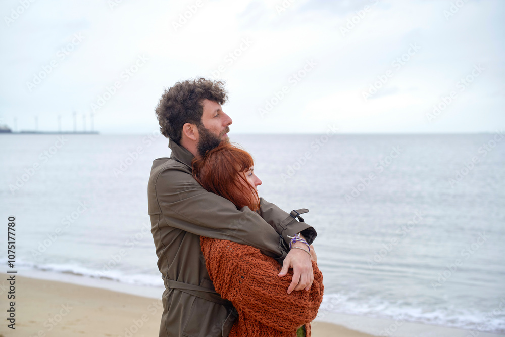 A couple embracing tenderly on a beach under an overcast sky, Belgium A couple embracing tenderly on a beach under an overcast sky, Belgium
