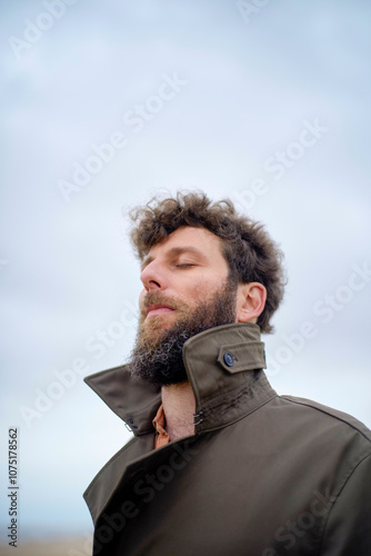 Close-up of a bearded man with his eyes closed, breathing in outdoor air, wearing a brown jacket, Belgium photo