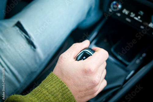 Close-up of a person's hand shifting a car's gear stick while driving. photo