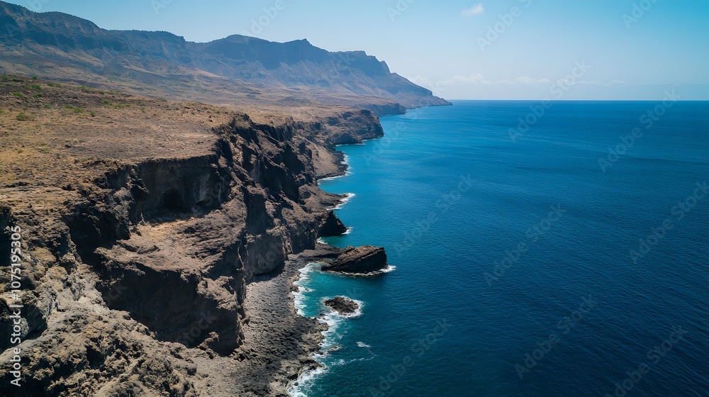 Fototapeta premium High perspective of a rocky coastline with cliffs meeting the ocean in a balanced, dramatic landscape with a perfect division between land and sea. No text, no logo, wide angle shot, cinematic scene,