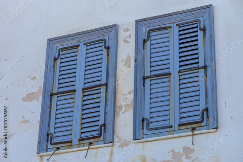 Charming blue shutters on a weathered wall in a quaint coastal village at twilight.