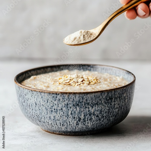 A hand sprinkling inulin powder into a bowl of oatmeal, promoting digestive and gut health photo