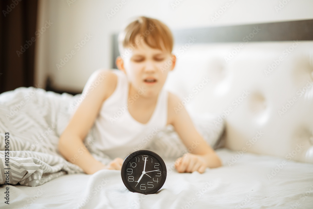 Kid boy teenager waking up yawning and stopping alarm clock in morning Kid boy teenager waking up yawning and stopping alarm clock in morning