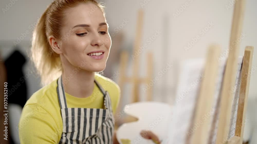 Happy blonde woman drawing picture in school of art, portrait in workshop. Beautiful Caucasian female student or professional artist working in studio, positive emotions and good mood by art therapy Happy blonde woman drawing picture in school of art, portrait in workshop. Beautiful Caucasian female student or professional artist working in studio, positive emotions and good mood by art therapy