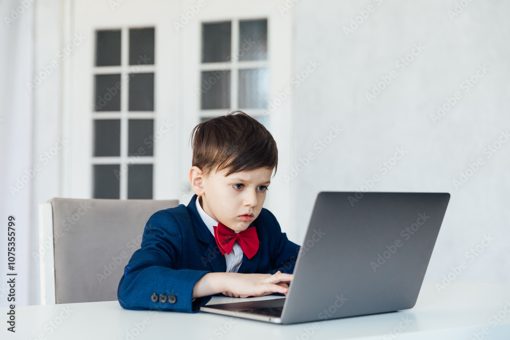 Schoolboy In Jacket At Desk Playing In Laptop Online Schoolboy In Jacket At Desk Playing In Laptop Online