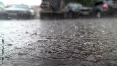 Rain falling on asphalt creating puddles in parking lot