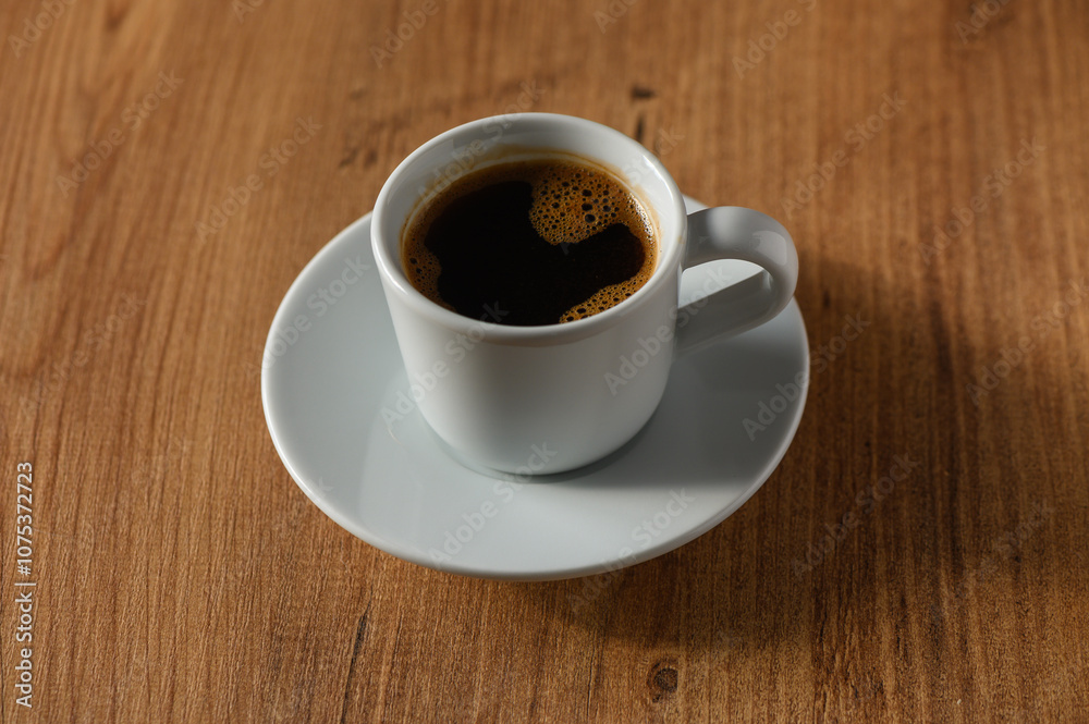 A quiet moment with a steaming cup of coffee resting on a wooden table in the soft morning light A quiet moment with a steaming cup of coffee resting on a wooden table in the soft morning light