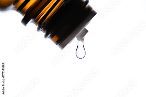 A drop of antihistamine or essential oil drips from a bottle. Close-up. photo