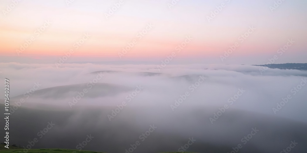 Obraz premium Early morning fog rolling over the hills with soft pink hues of sunrise, soft focus, misty atmosphere, landscape