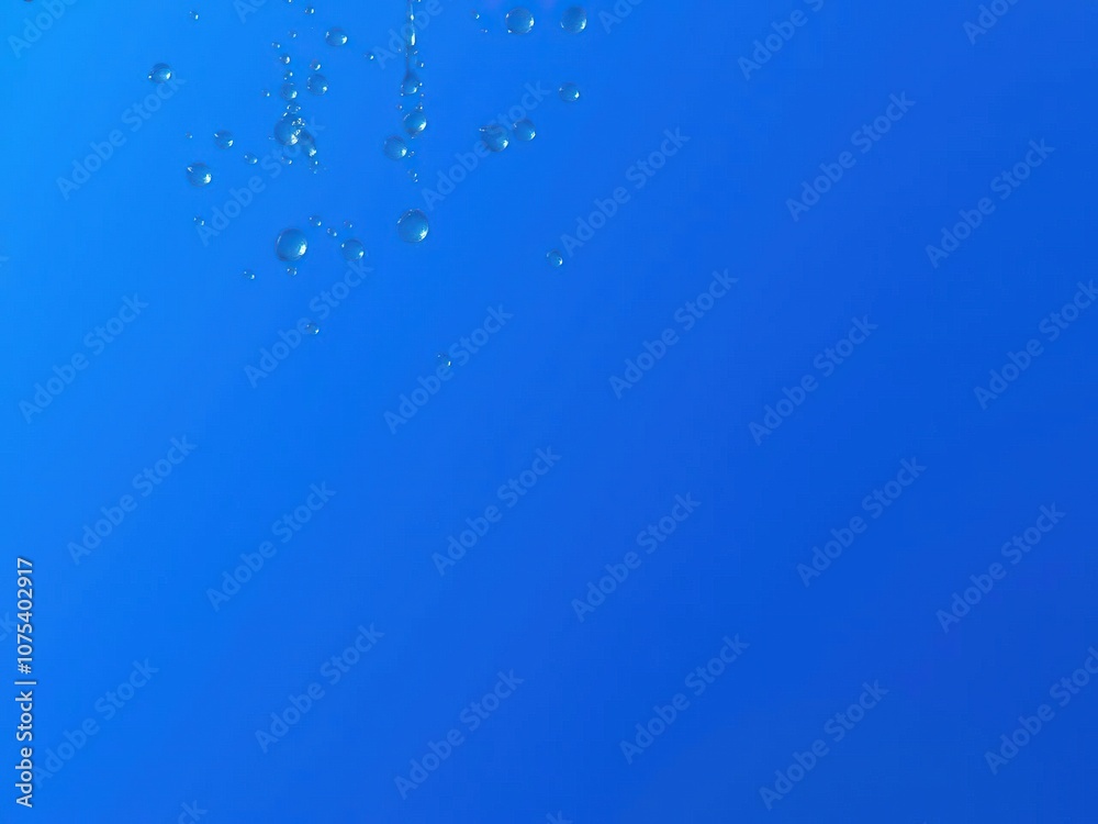 Water droplets suspended in mid-air on a blue background with slight ripples and vibrations, transparent liquids, fluid dynamics Water droplets suspended in mid-air on a blue background with slight ripples and vibrations, transparent liquids, fluid dynamics