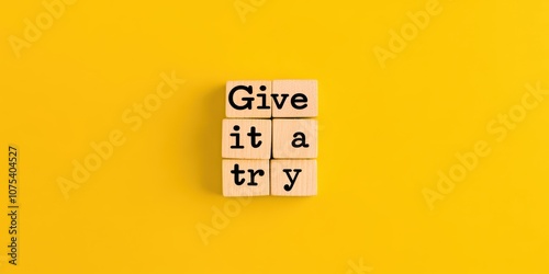 “Give it a try” message on wooden blocks with yellow background, motivational theme.