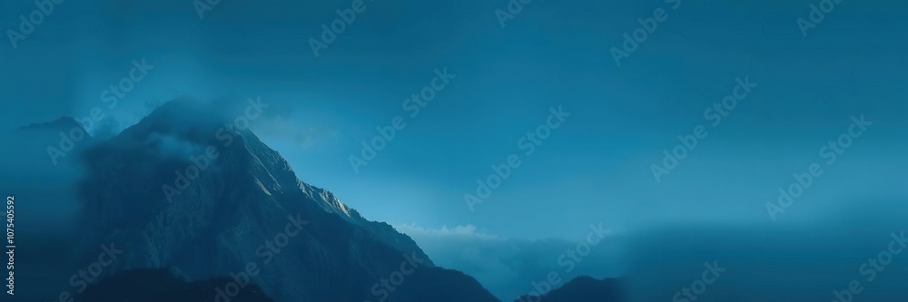 Fototapeta premium A majestic mountain peak with a dark blue gradient of mist and cloud, outdoorphotography, misty, bluedeviation