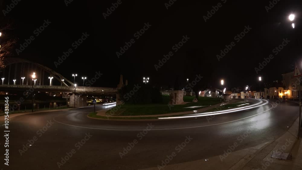 Time lapse of light trails from vehicles moving along a curved road near a bridge, illuminated by streetlights at night next to the bridge. Time lapse of light trails from vehicles moving along a curved road near a bridge, illuminated by streetlights at night next to the bridge.