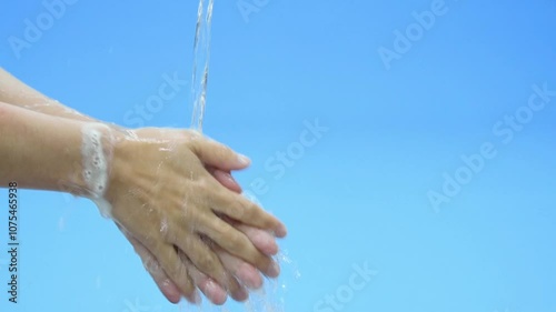 Slow motion of asian woman cleaning hands with white soap bubbles on blue background