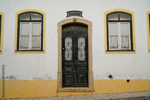 Wooden weathered old front door with mailbox with the Portuguese inscription for mail (correio), detail of a yellow and white house facade in the village of Vila do Bispo, Algarve, Portugal.