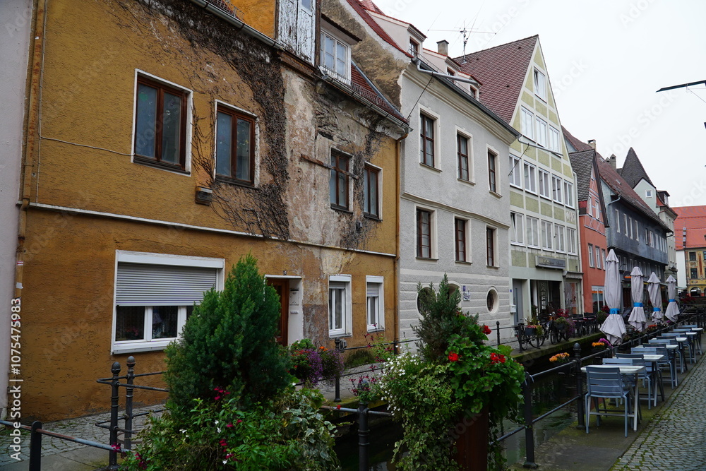 Fototapeta premium Colorful buildings on the sides of the small stream Memminger Ach and pedestrian bridges in the historic old town of Memmingen, Bavaria, Germany.