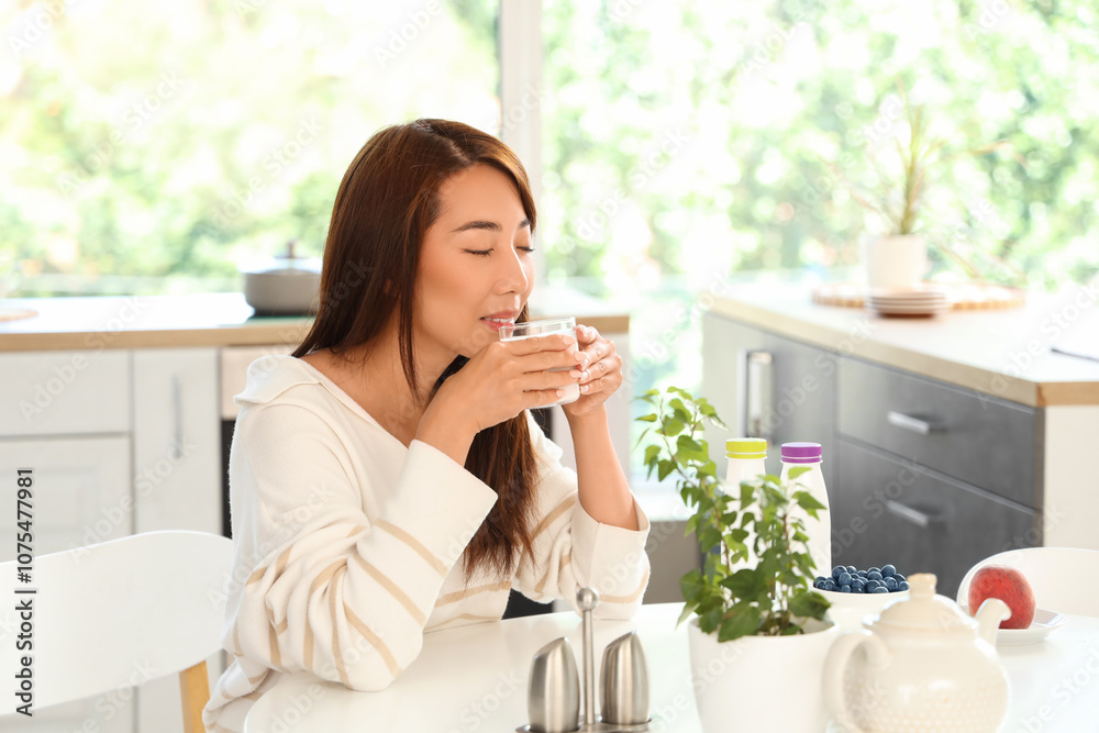 Pretty young Asian woman drinking tasty yogurt at home Pretty young Asian woman drinking tasty yogurt at home