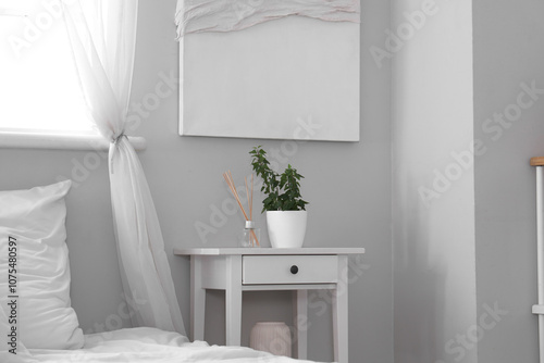 Stylish bedside table with decor near comfortable bed at home, closeup